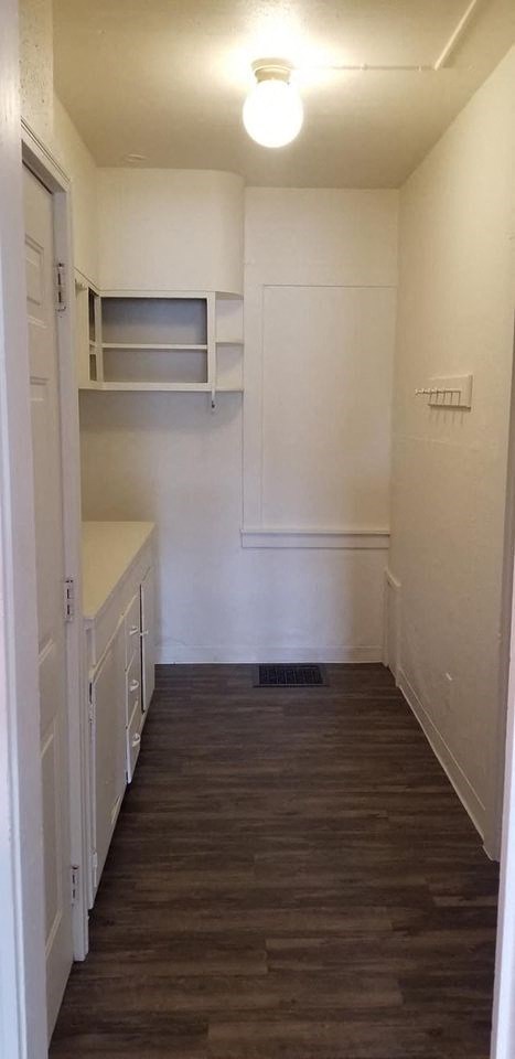 a small kitchen with a wood floor and white cabinets