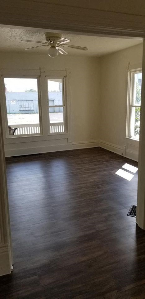 an empty living room with wooden floors and a ceiling fan