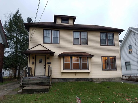 A two-story house with a brown roof and a white door.