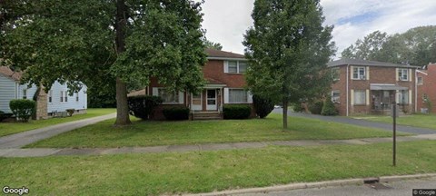 a house on a street with trees in front of it