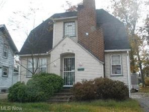 A house with a white siding and a brick chimney is for sale.