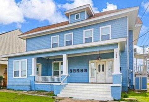 A blue house with white trim and a white door.