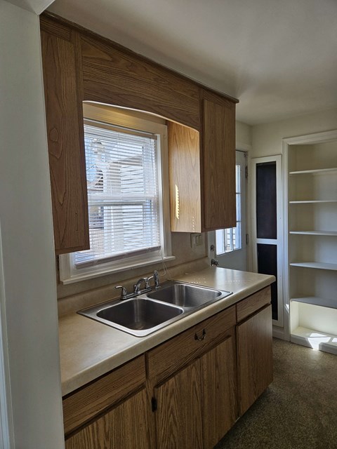 A kitchen with wooden cabinets and a window above the sink.
