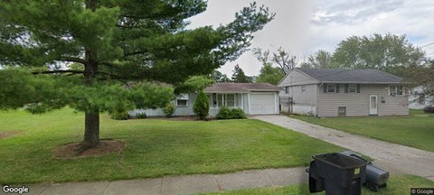 a house with a tree in the yard and a driveway