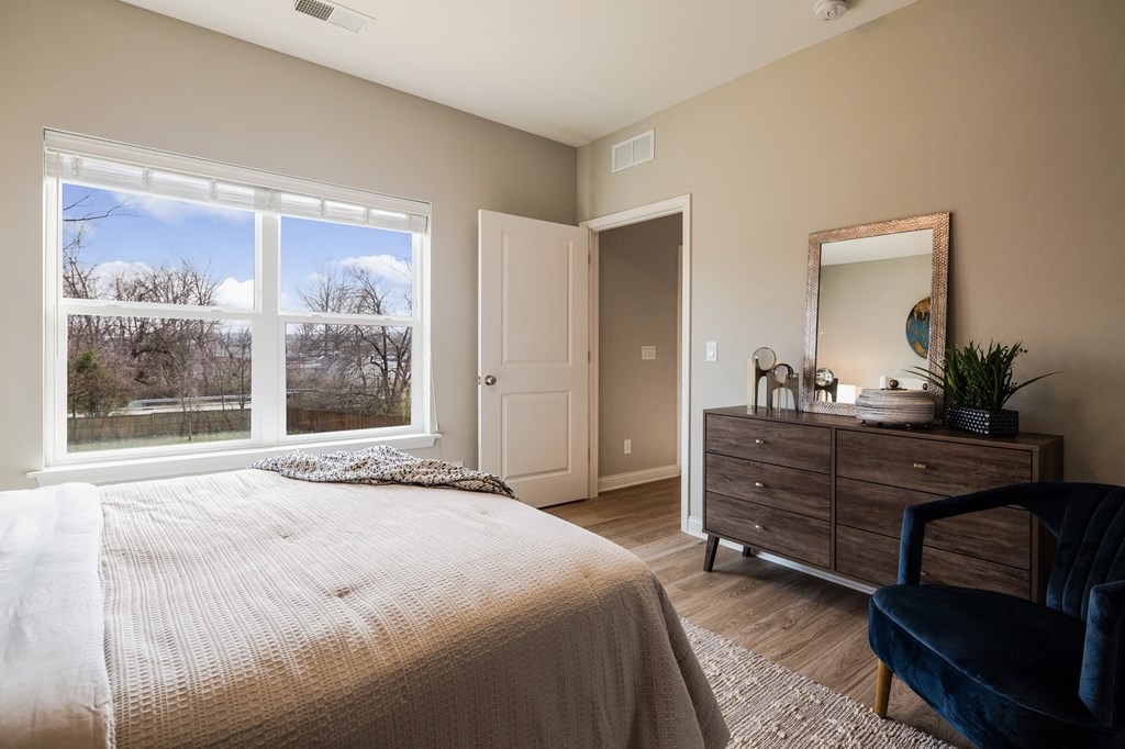 a bedroom with a large window and a bed and a dresser