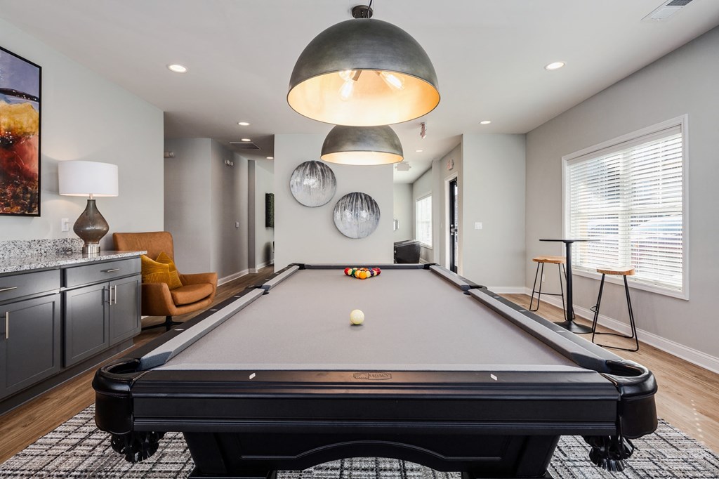 a pool table in a living room with a bar and a window