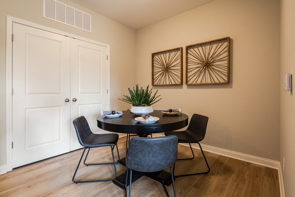 a dining room with a table and chairs and two paintings on the wall