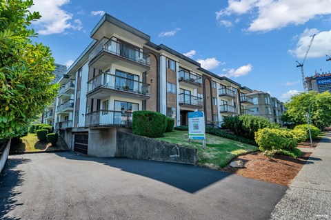 A multi-story residential building with a parking area in front.