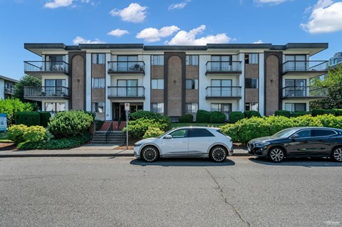 Two cars parked in front of a modern apartment building.