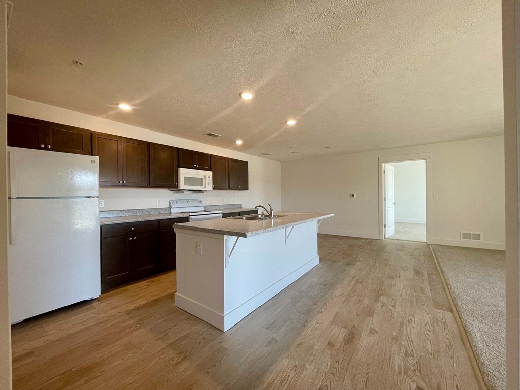 an empty kitchen with an island and a refrigerator
