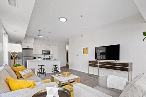 A modern living room with a grey couch, yellow pillows, and a wooden coffee table.
