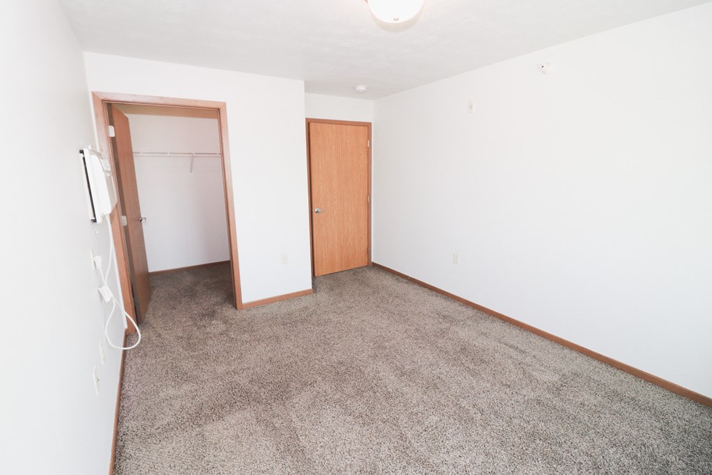 an empty living room with carpet and a door to a closet