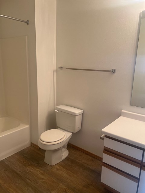 A white toilet in a bathroom with a white tub and a white sink.