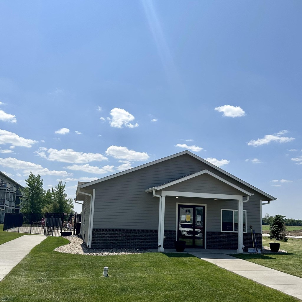 a small gray house with a lawn and a sidewalk
