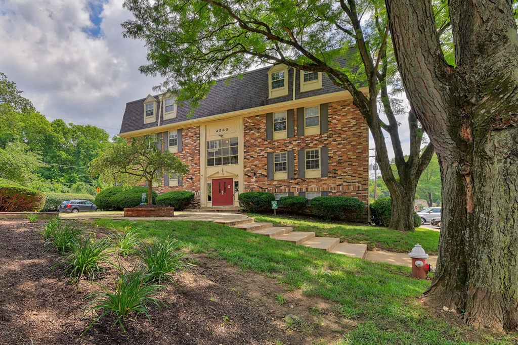 a home with a red door and a lawn and trees