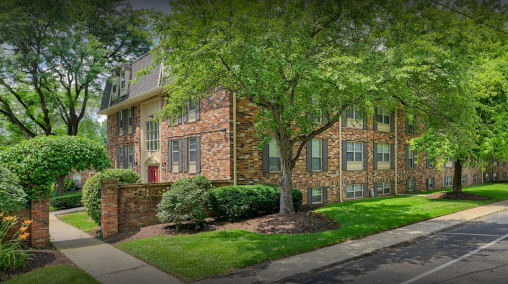 exterior view of a brick apartment building with green grass and trees
