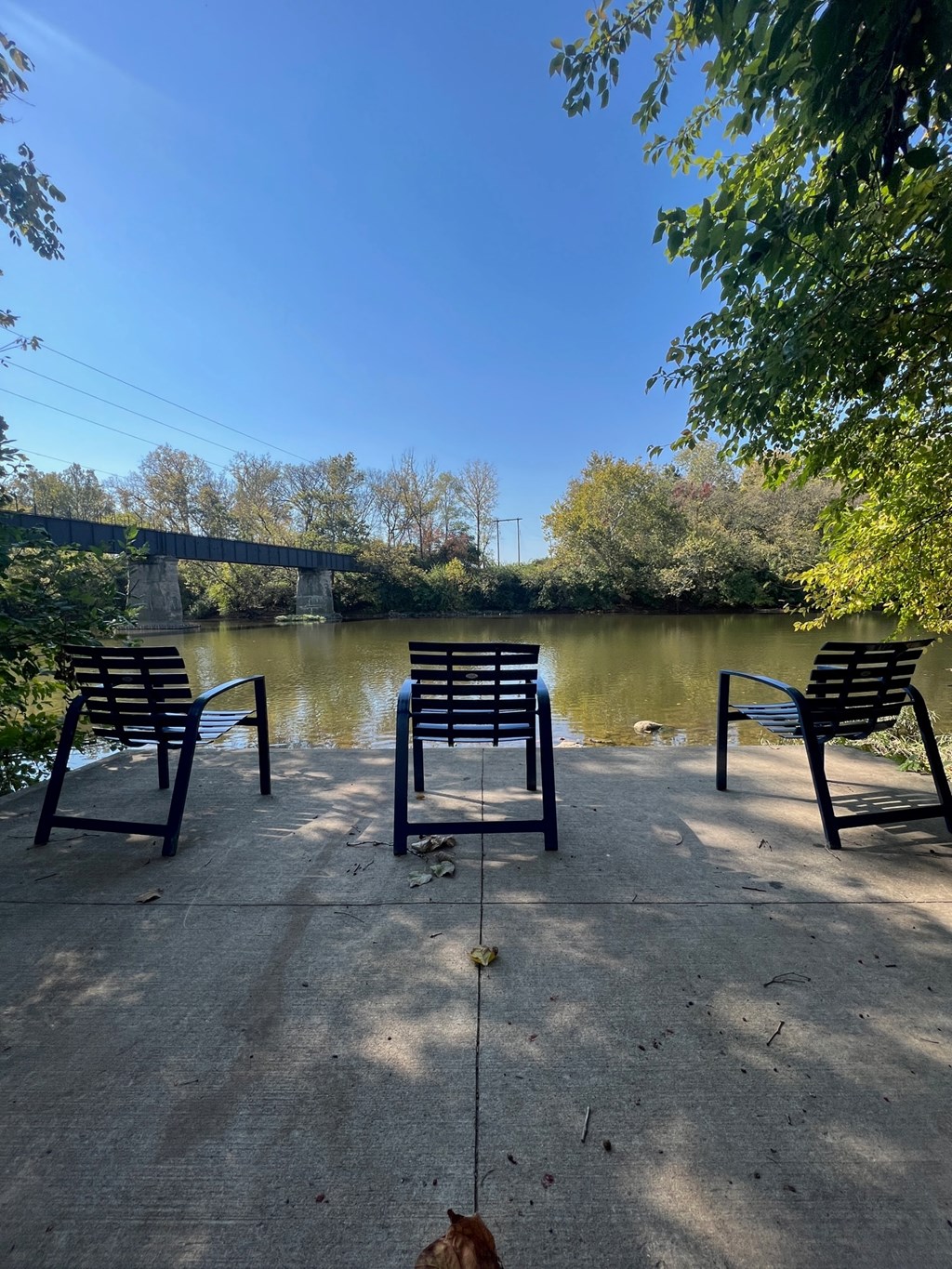 three park benches on a concrete slab overlooking the river