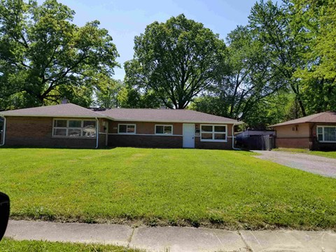 the front of a house with a lawn and trees