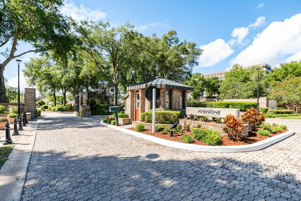 a park with a sign and trees and a brick walkway