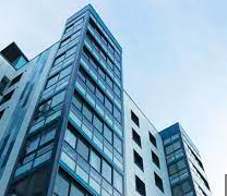 a tall glass building with a blue sky in the background