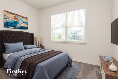 A bedroom with a large bed and a painting on the wall.