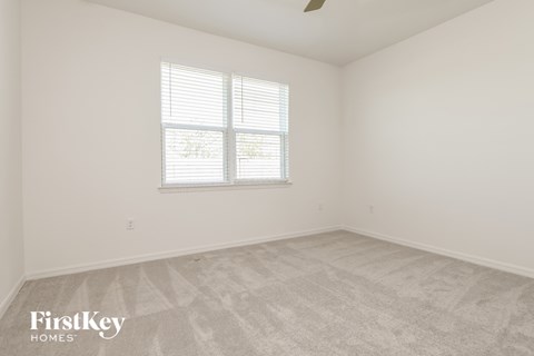 the living room of a home with white walls and carpet and a window