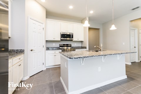 A kitchen with a granite countertop and white cabinets.