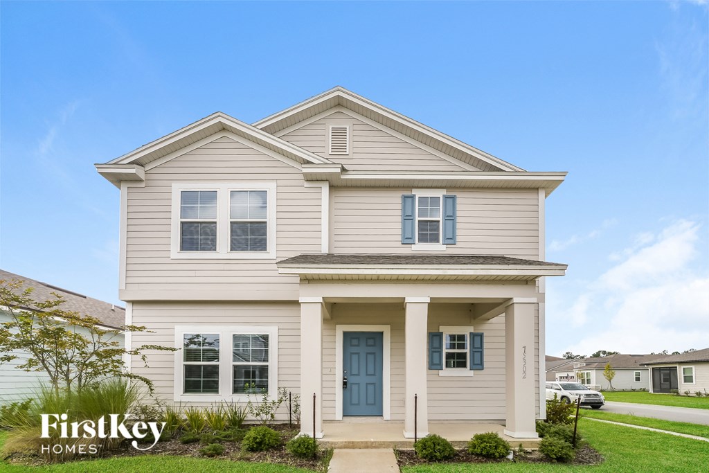a beige house with blue doors and a lawn