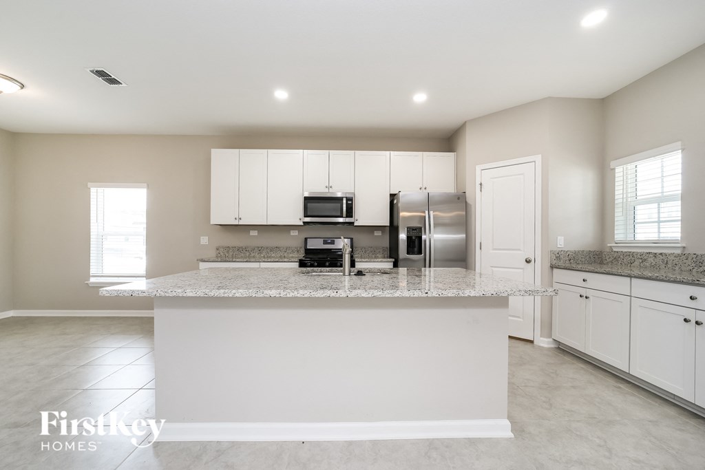 a large kitchen with white cabinets and a granite counter top