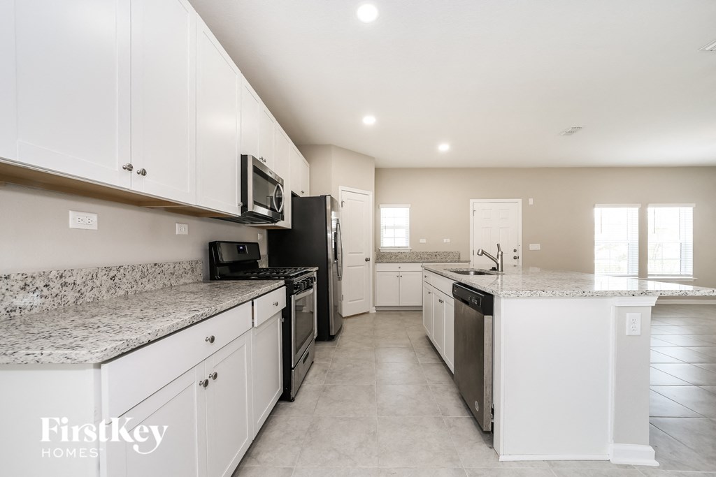 a large kitchen with white cabinets and granite counter tops