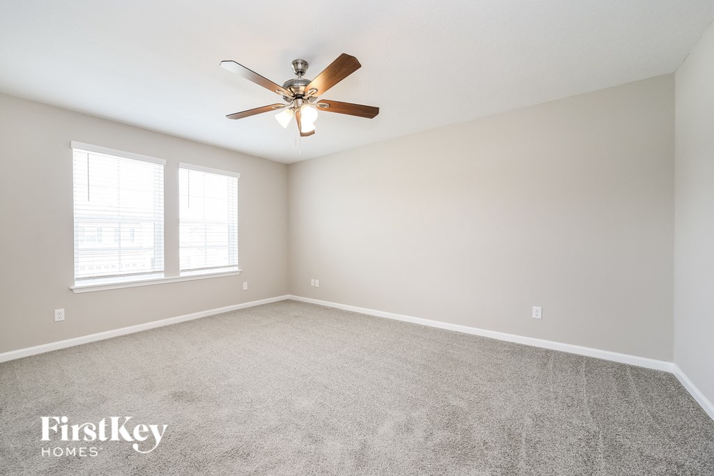 an empty living room with a ceiling fan and a window