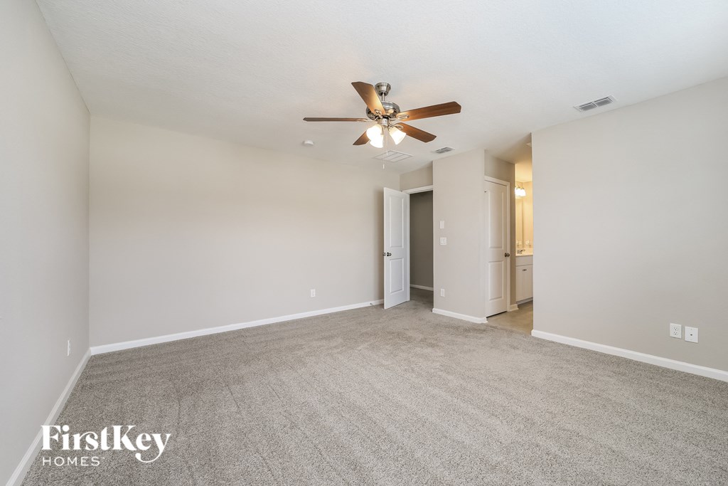 a spacious living room with carpet and a ceiling fan