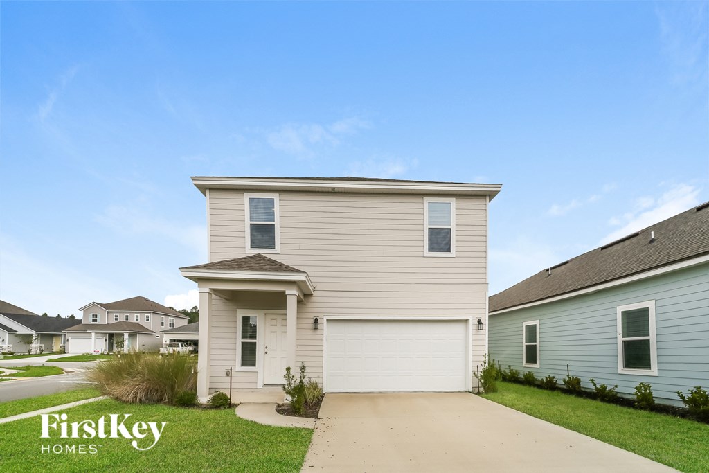 a beige house with a white garage door and a driveway