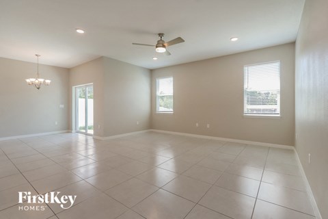 an empty living room with a ceiling fan and tiled floors