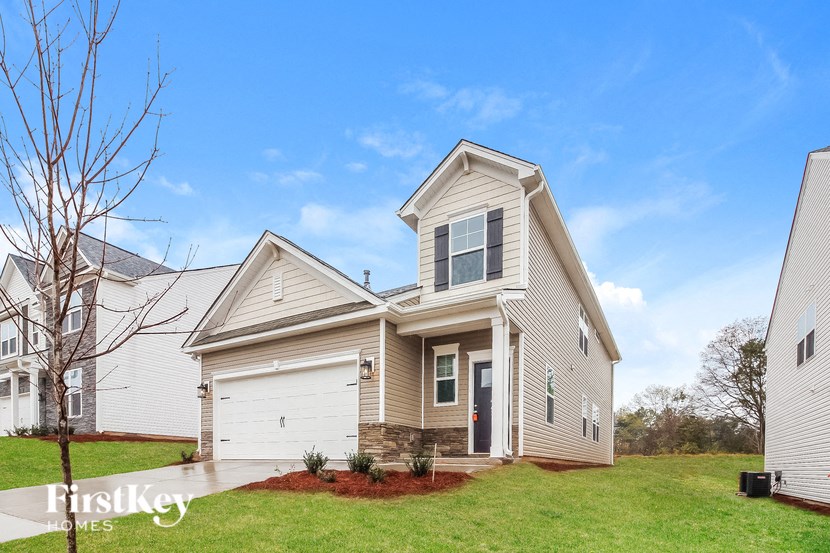 a beige house with a white garage door and a green lawn