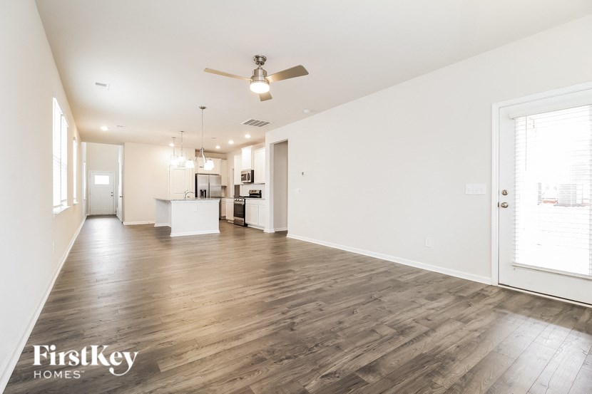 a living room and kitchen with wood flooring and a ceiling fan
