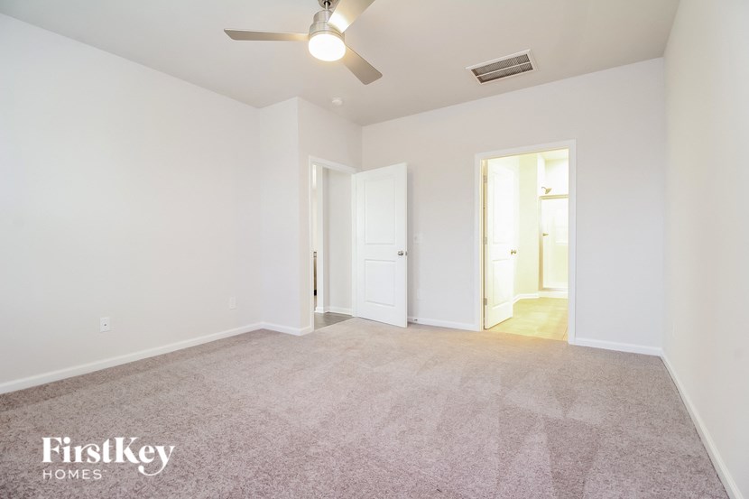 an empty living room with white walls and a ceiling fan