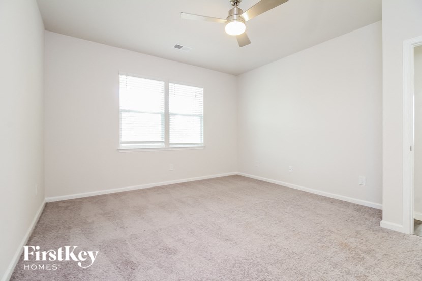 an empty room with a ceiling fan and a window