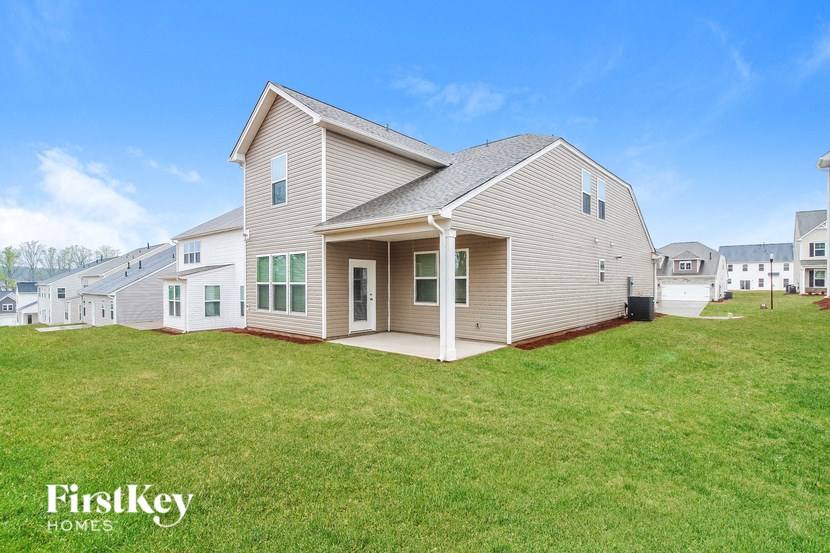 a white house with a yard and some houses in the background