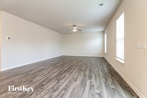 A spacious room with wooden flooring and a ceiling fan.