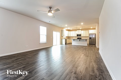 A spacious room with wooden flooring and a ceiling fan.