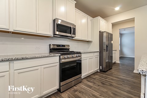 A kitchen with white cabinets and a stainless steel refrigerator.
