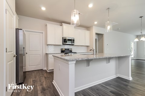 A kitchen with a refrigerator, microwave, and cabinets.
