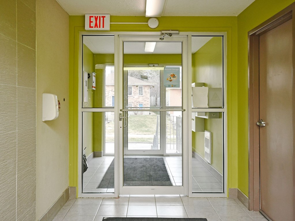 A hallway with a green wall and a white door with a glass window.