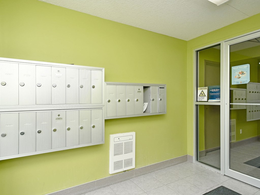 A row of white mailboxes on a green wall.