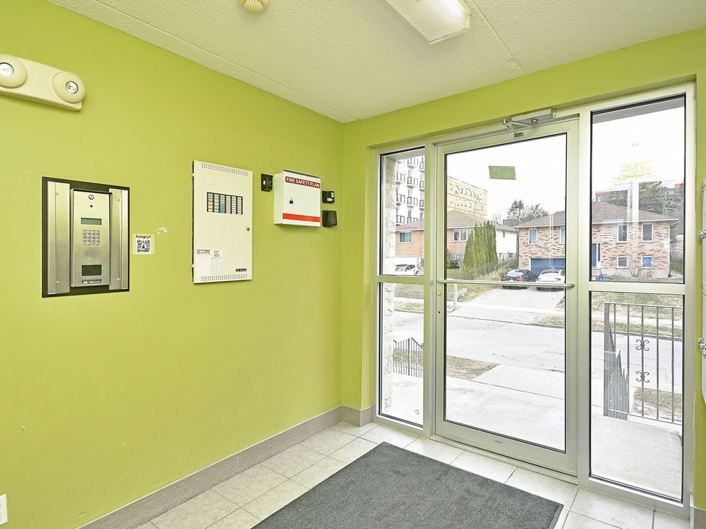 A hallway with a green wall and a glass door leading outside.