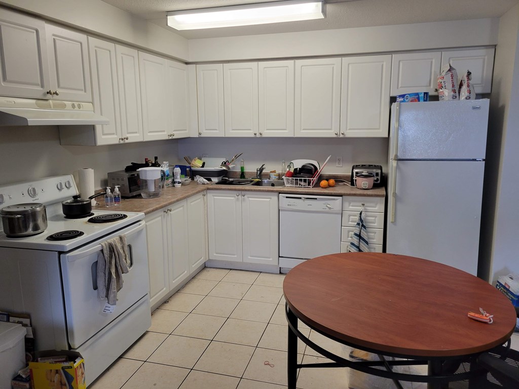 A kitchen with white appliances and wooden table.