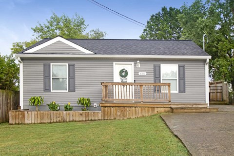 the exterior of a gray house with a deck and a porch