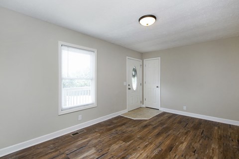 an empty living room with wood floors and a white door