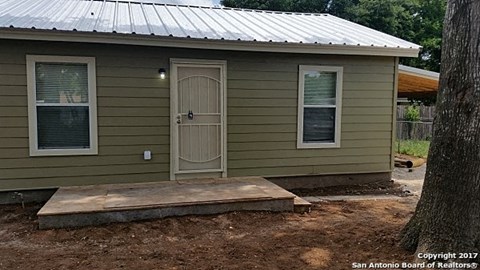 a small green house with a porch and a door